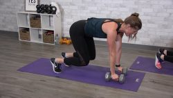 Woman holding a bear plank with dumbbells