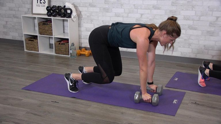 Woman holding a bear plank with dumbbells