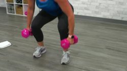 Doing a squat with pink dumbbells