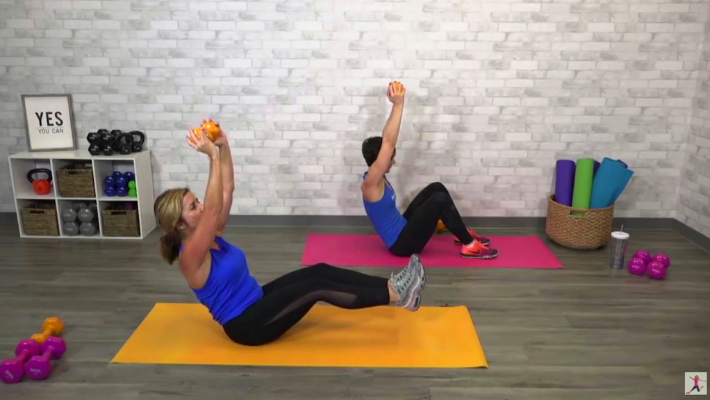Two women doing an ab workout with dumbbells