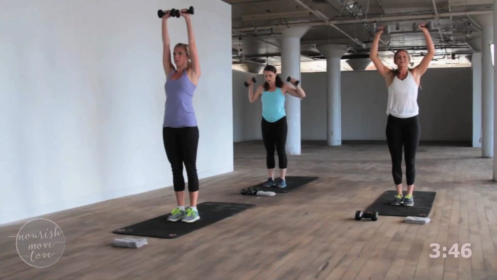 Three women doing a dumbbell workout in a warehouse