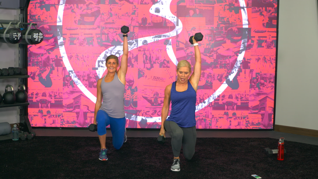 Two women doing lunges with a dumbbell overhead
