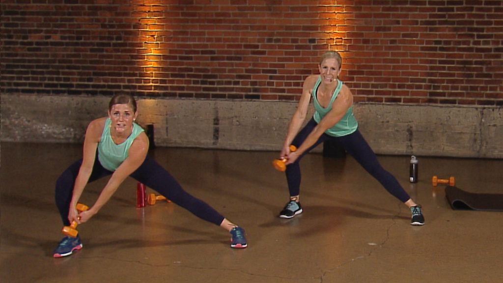 Two women doing side lunges with dumbbells