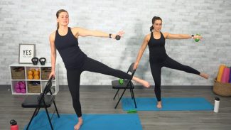 Two women in all black doing barre with weights and a chair