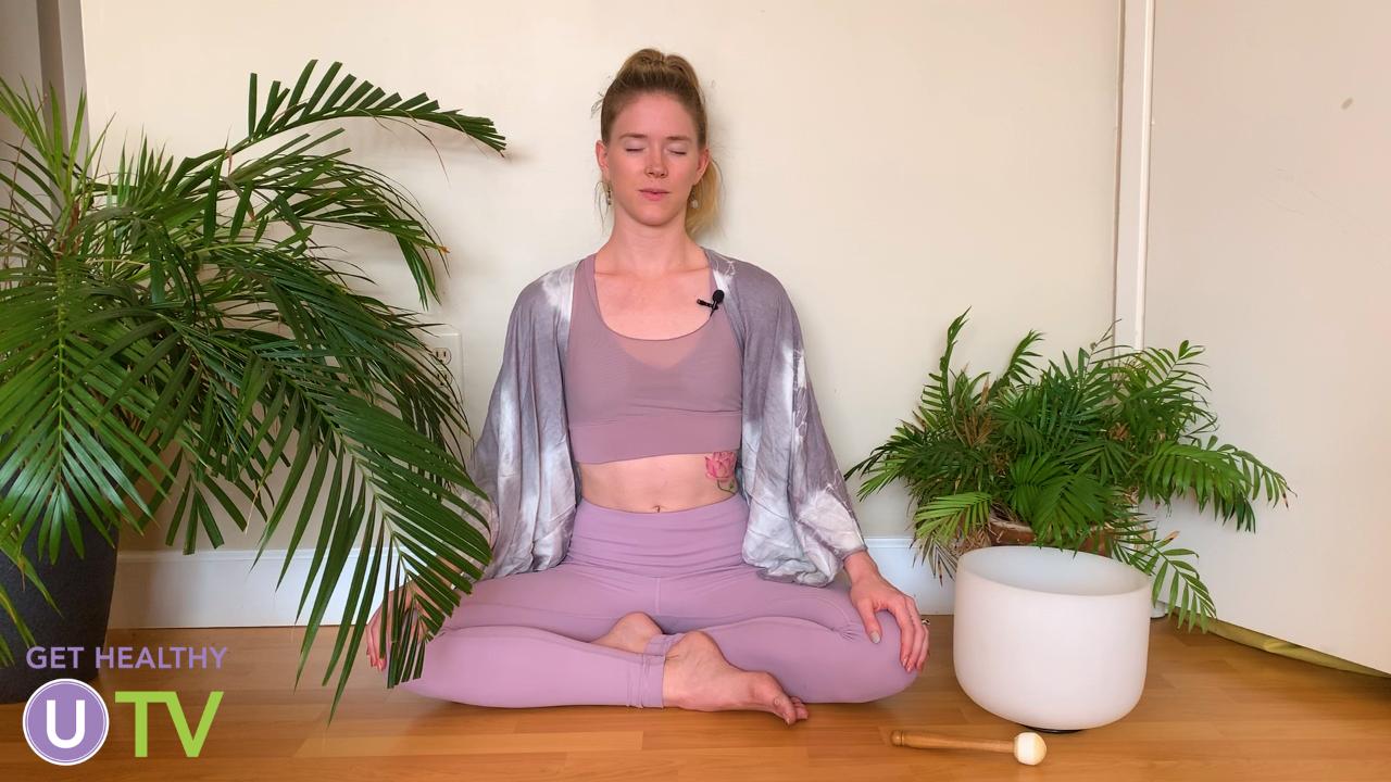 Woman meditating on the floor surrounded by plants