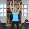 Woman in a blue tank top working out with dumbbells