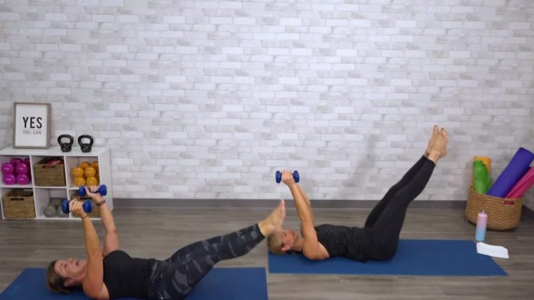 Two women doing a core workout with weights