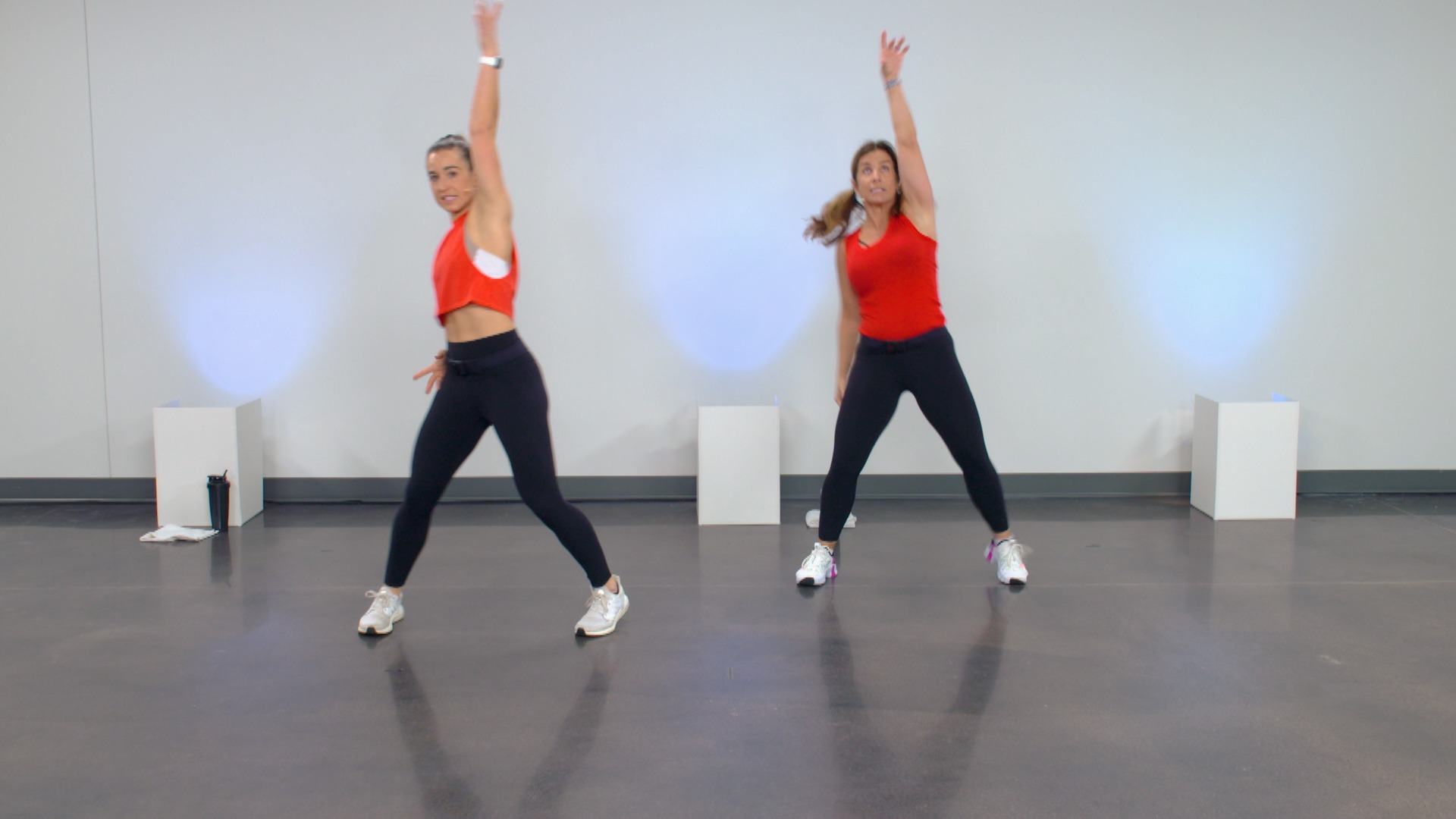 Two women wearing red tops doing a dance workout