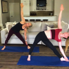 Two women doing a yoga pose in a living room