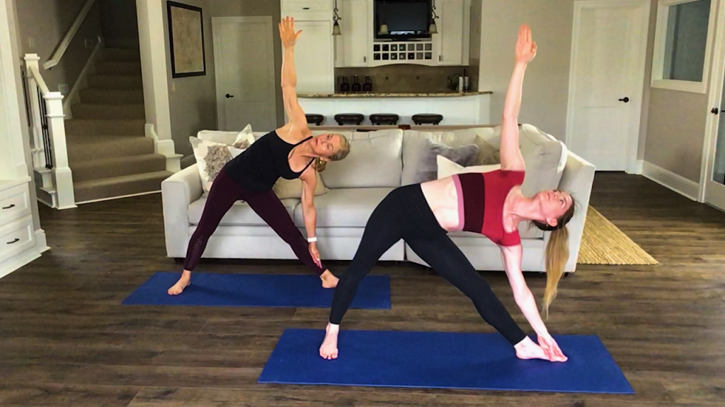 Two women doing a yoga pose in a living room