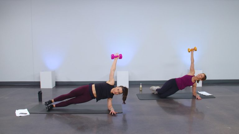 Two women doing a side plank holding a dumbbell