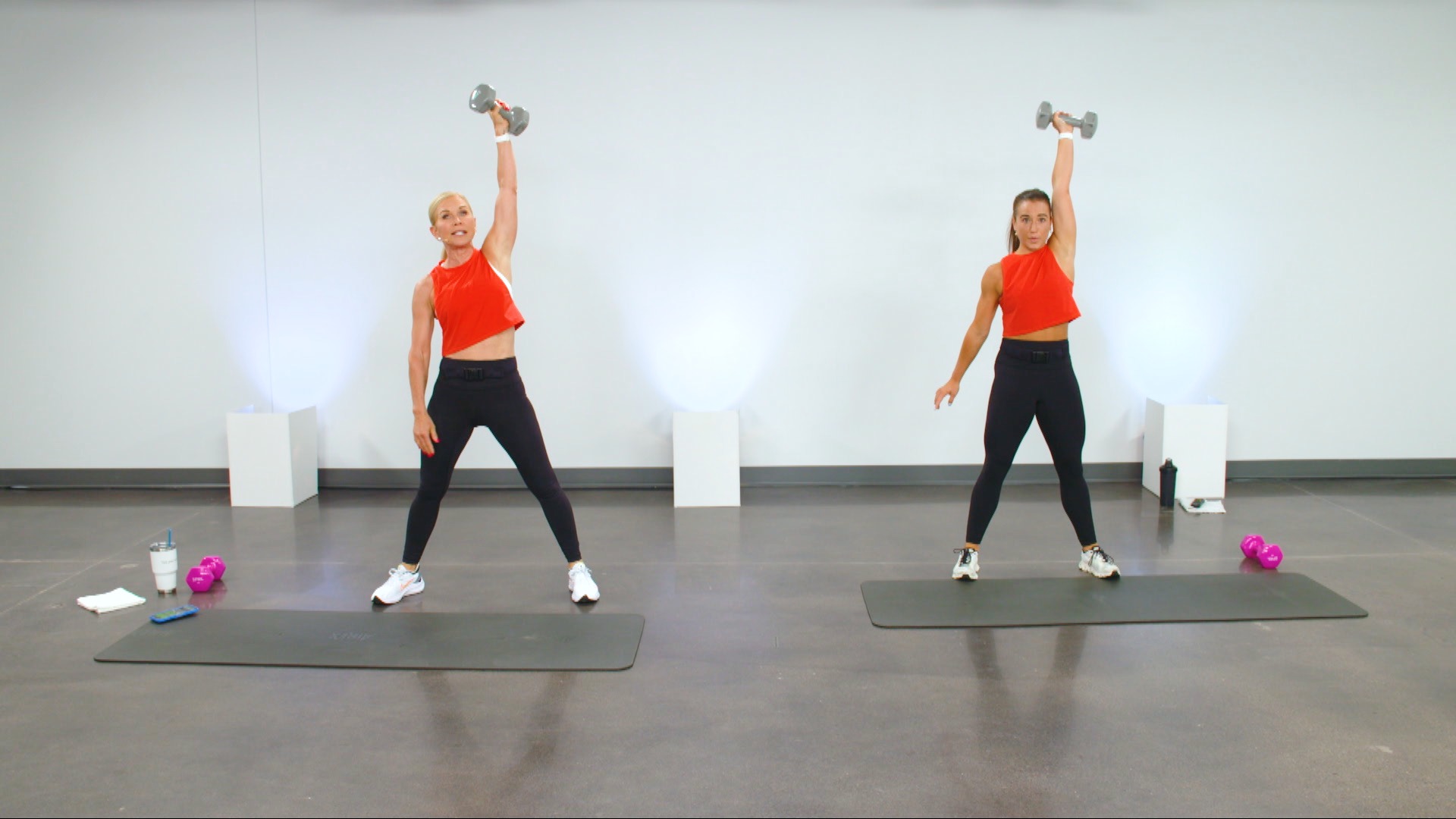 Two women working out with a dumbbell in one hand