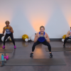 Three women doing squats with a dumbbell