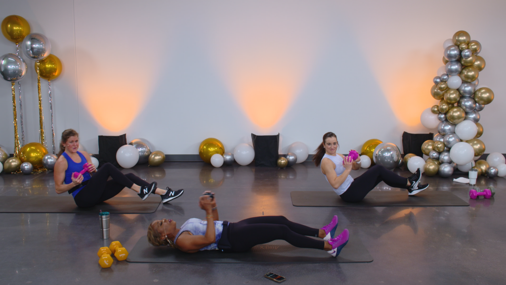 Three women doing core work with dumbbells