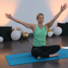 Woman doing yoga on a blue workout mat in a room with balloons