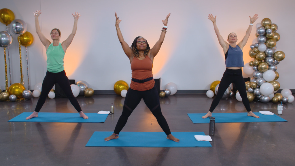 Three women doing yoga in a room of silver, gold and white balloons