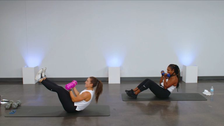 Two women doing core work with dumbbells