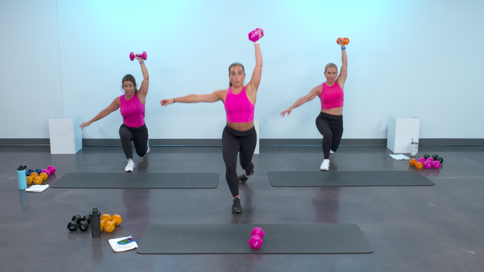 Three women wearing pink shirts working out with a dumbbell