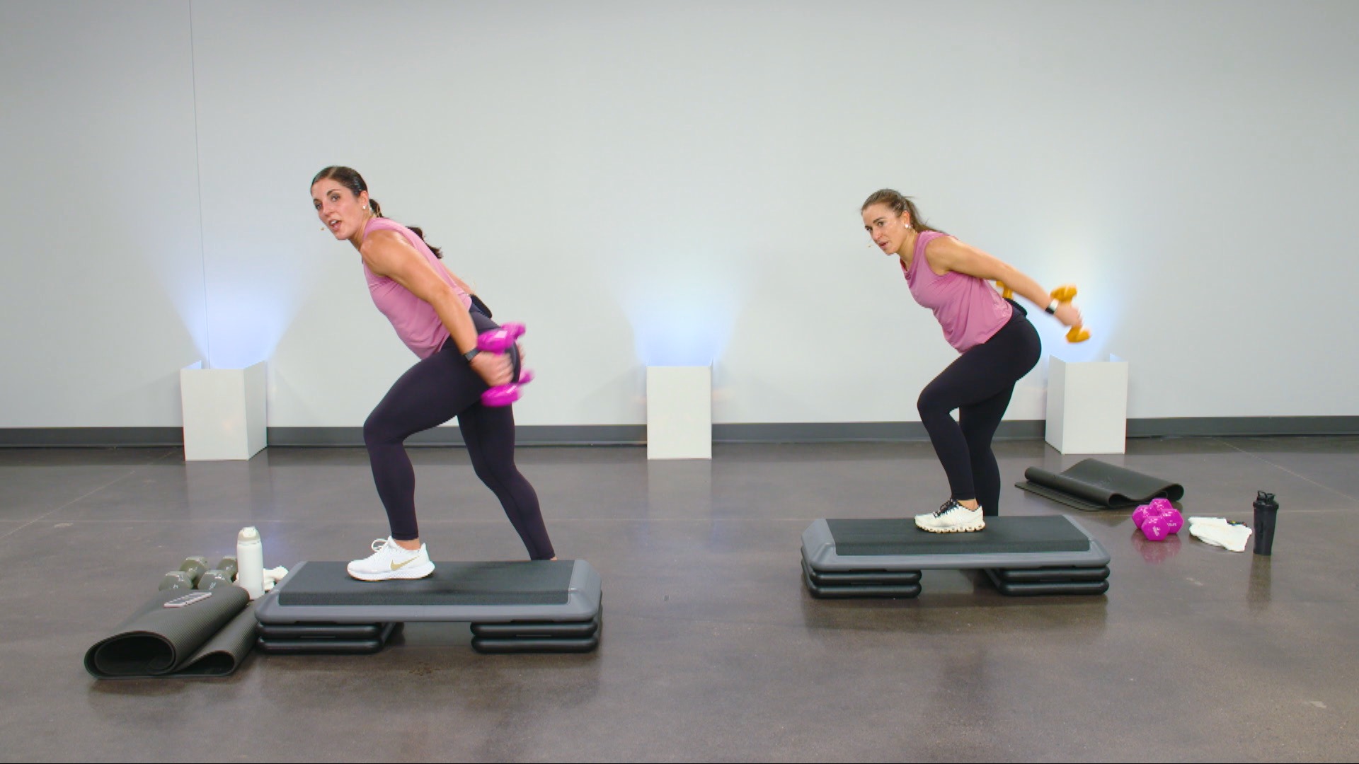 Two women working out on a step with dumbbells