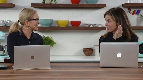 Two women talking at laptops