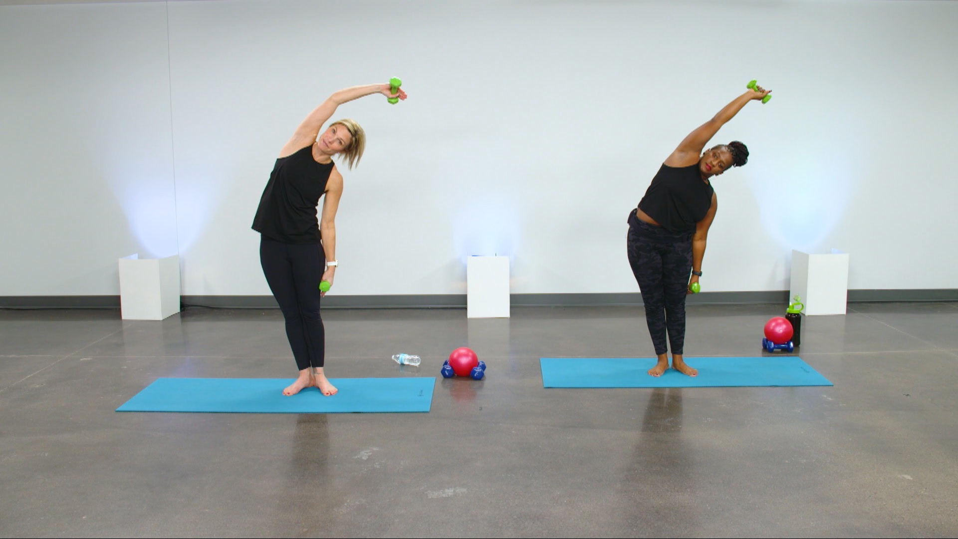 Two women doing a pilates workout with a small dumbbell