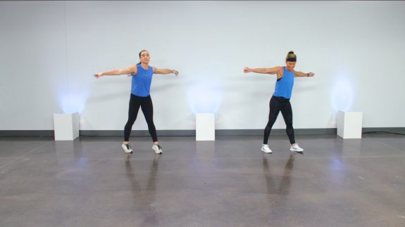 Two women in blue tank tops doing a dance workout