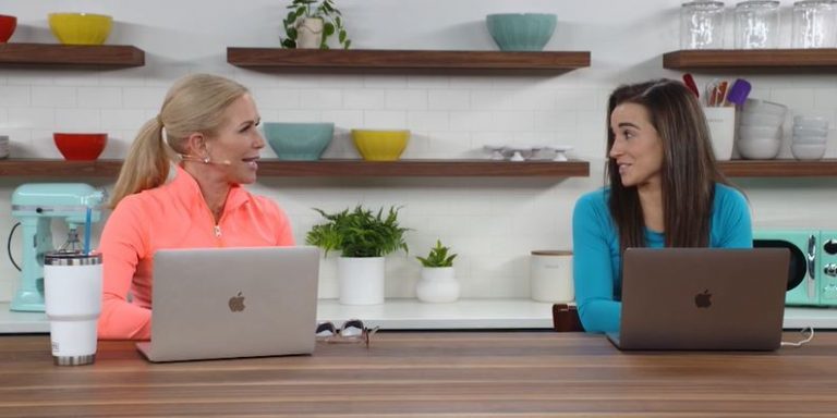 Two women with laptops open talking to each other