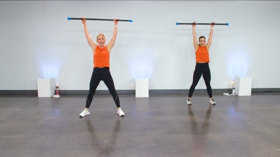 Two women working out with weighted bars