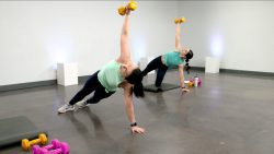 Two women doing side arm planks with a weight