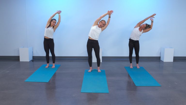 Three women doing yoga on blue exercise mats