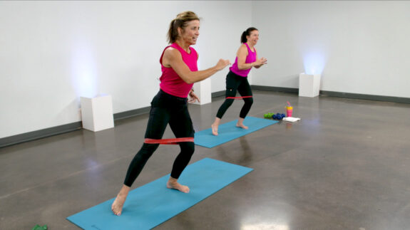 Two women working out with mini bands on blue mats