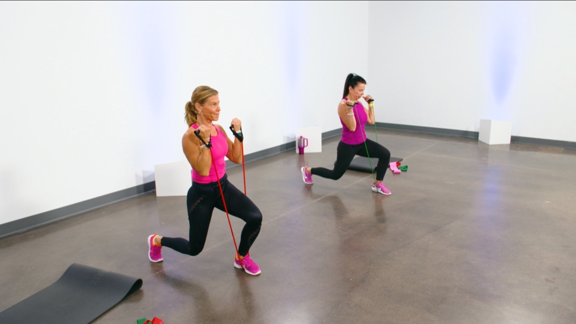 Two women doing lunges with resistance bands