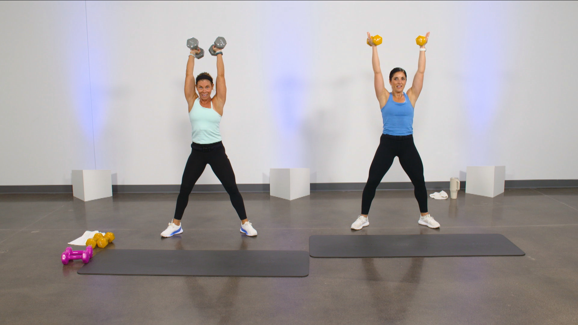 Two women doing dumbbell overhead presses