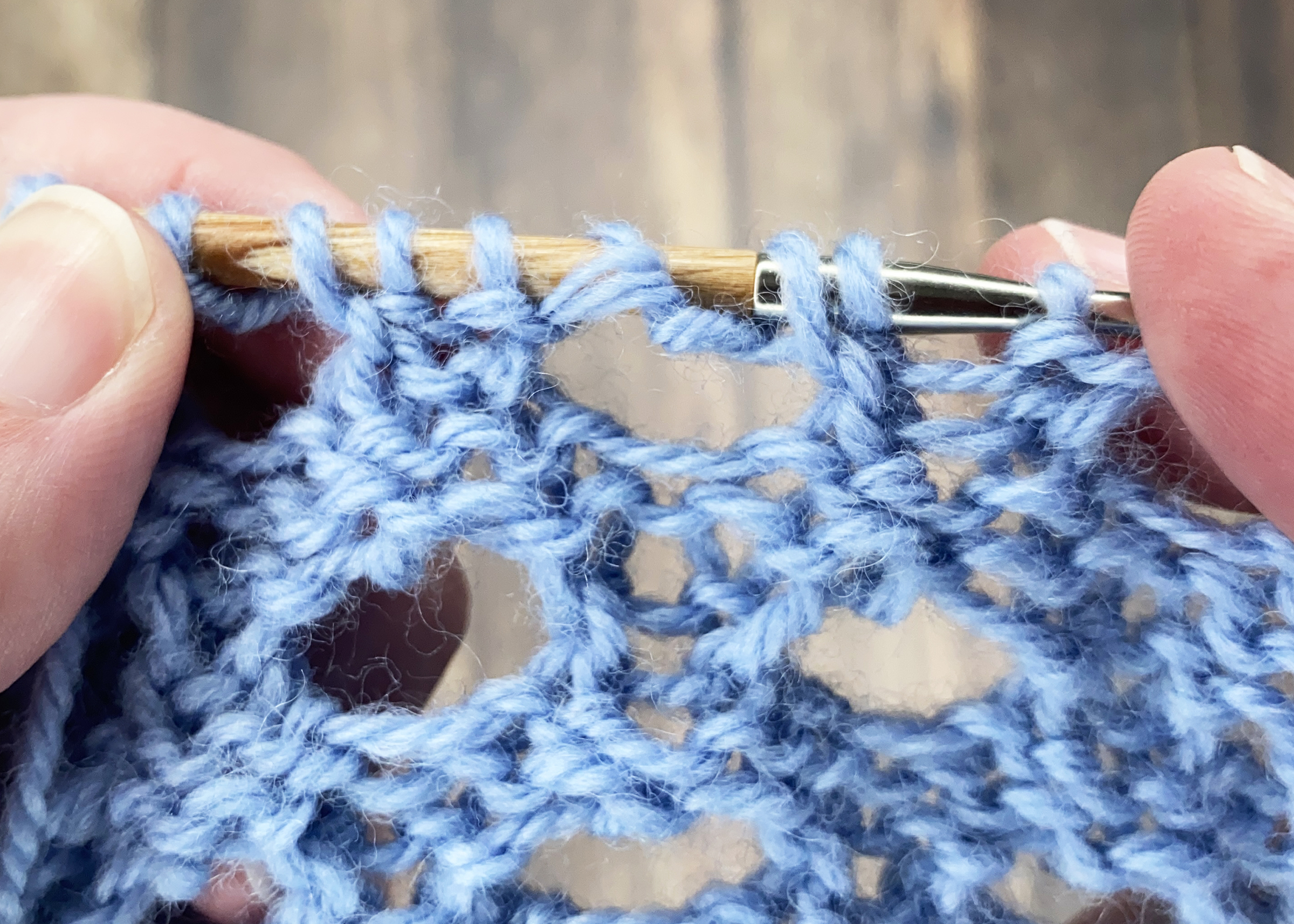 a close up of a completed double yarn over stitch with blue yarn