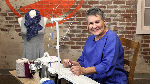 Woman at a table doing machine knitting