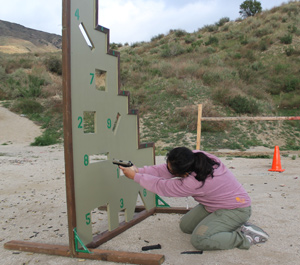 a woman shooting behind a cover for protection