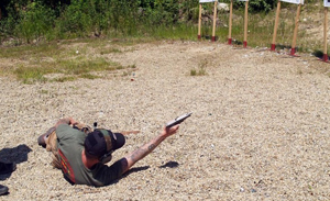 Man practicing shooting on the ground while lying on his side