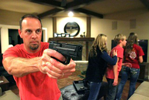 Man preparing to shoot while protecting his family behind him