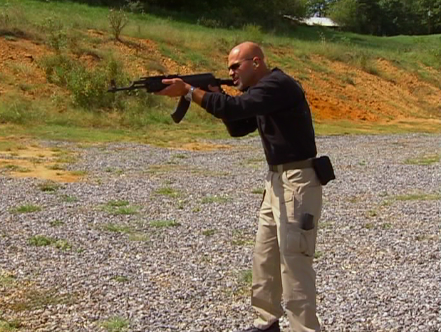 Man outside holding a large gun