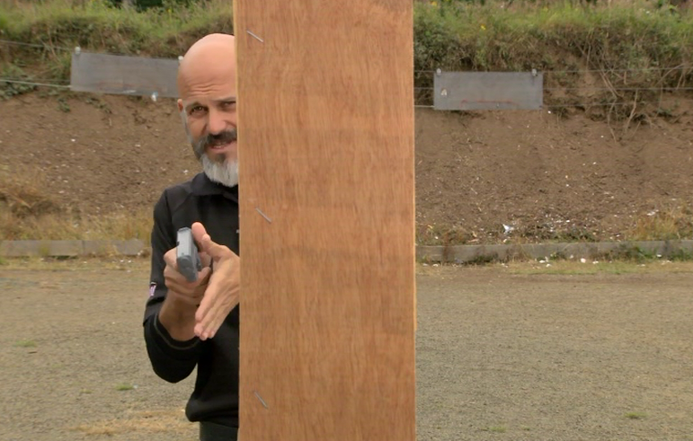 Man aiming a pistol around a board