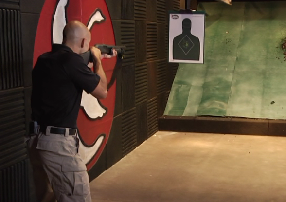 Man with a pump shotgun aiming at an indoor target