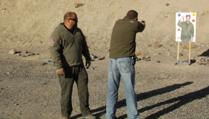 Two men shooting at an outdoor target of a person