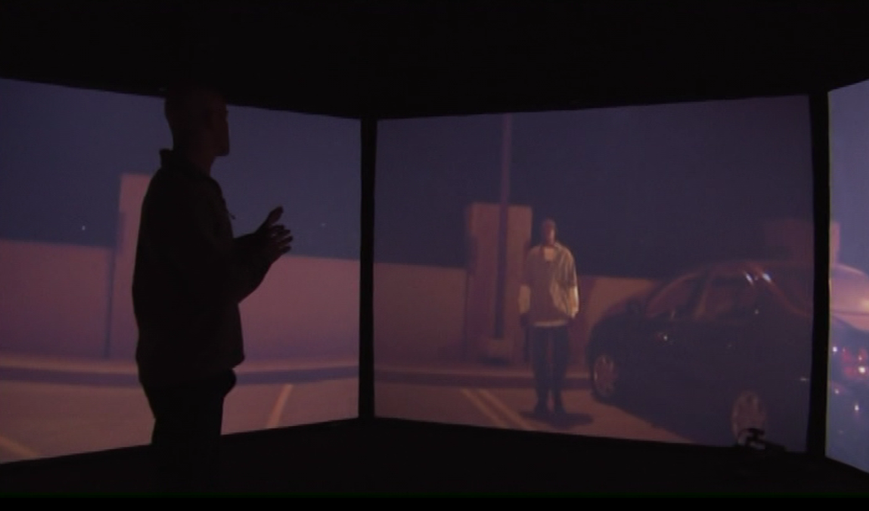 Man in front of screens showing someone in a parking lot at night