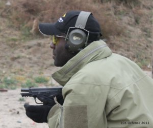 Man wearing hearing protection and gloves holding a gun