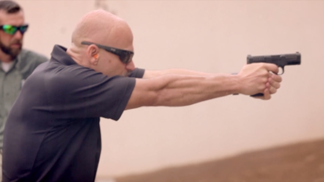 Man wearing protective eyewear aiming a pistol