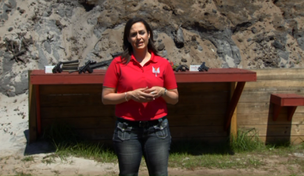 Woman talking outside with guns on a table behind her