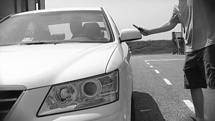 Black and white photo of a man attacking a car with a knife