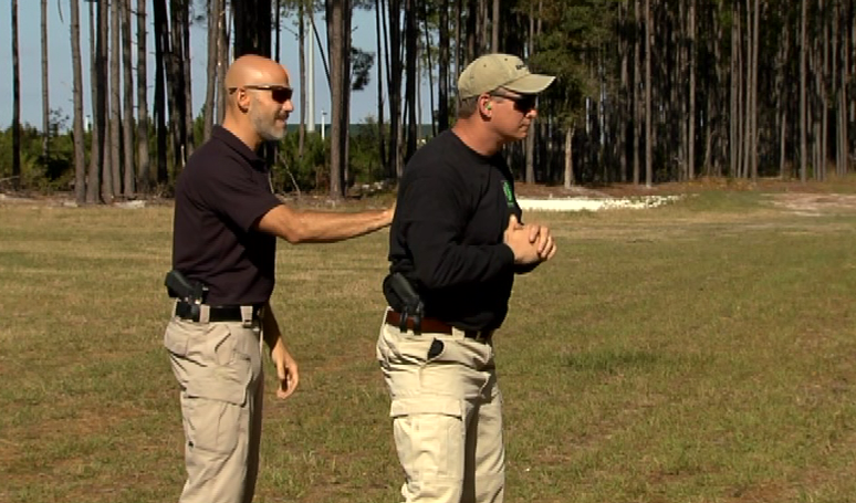 Two men outside with guns in their waistband