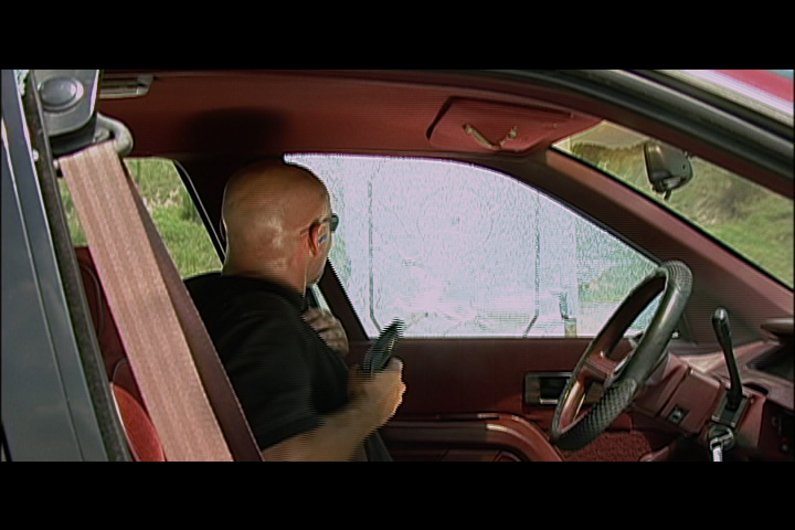 Man in a car aiming a gun out the window