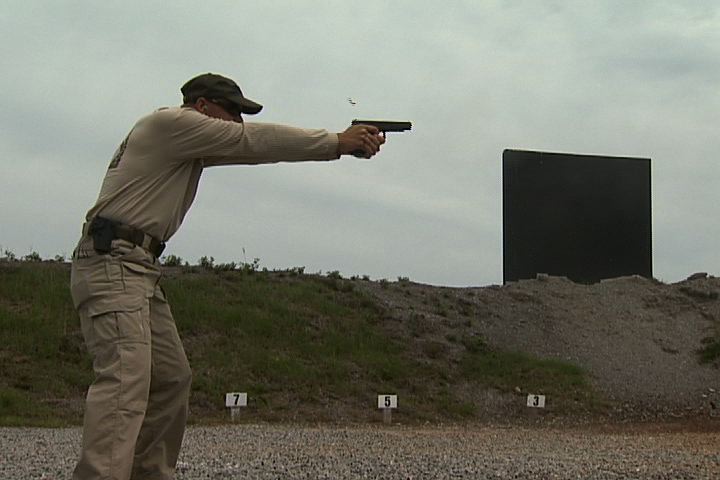 Man aiming a gun outside
